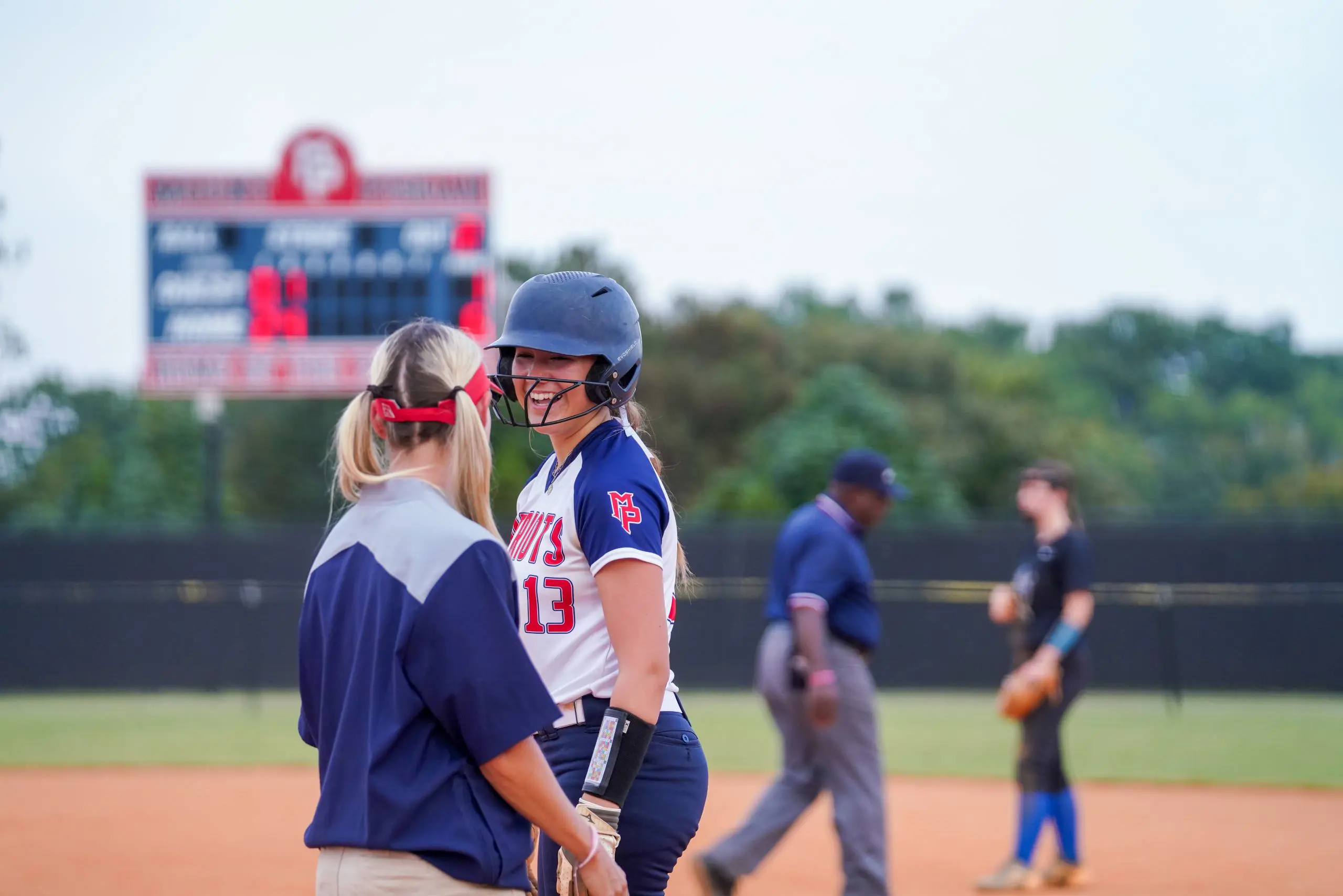 Softball player talks to coach on the field