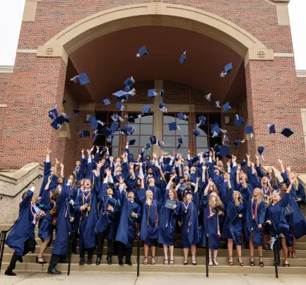 A group of high school graduates throw their graduation caps in the air