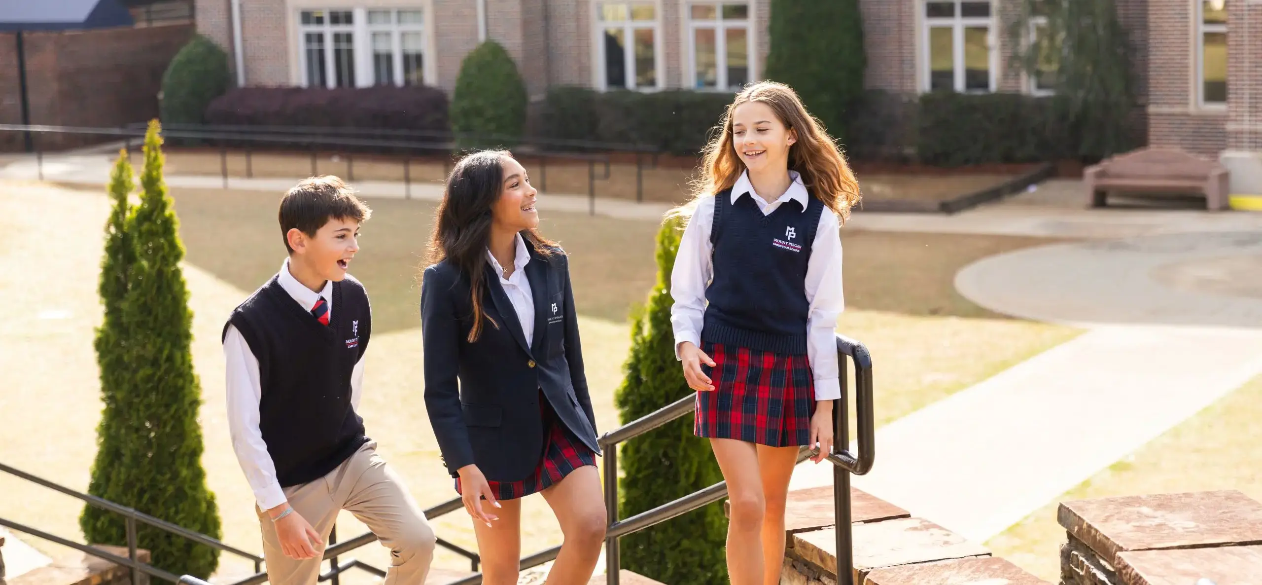 Three students walking outside, smiling