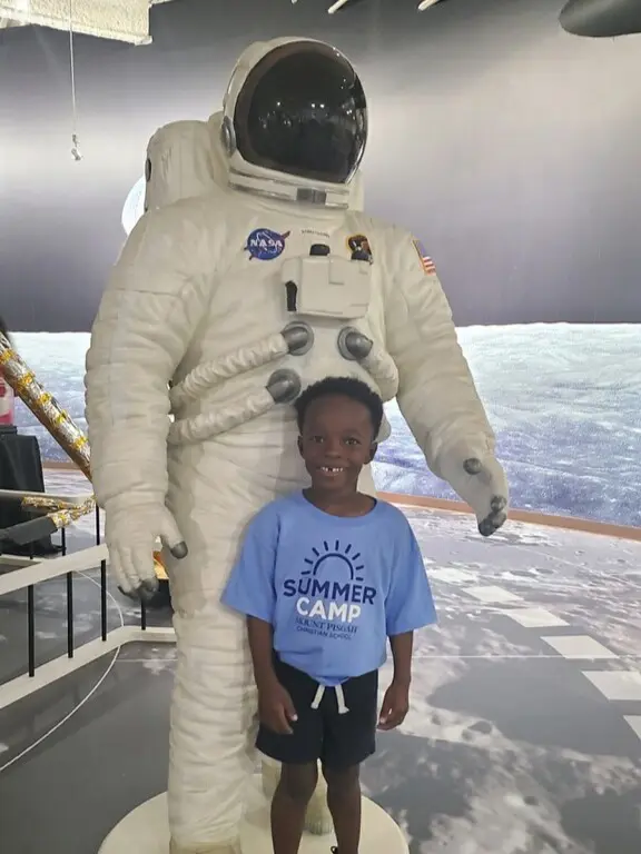 Child standing in front of astronaut statue