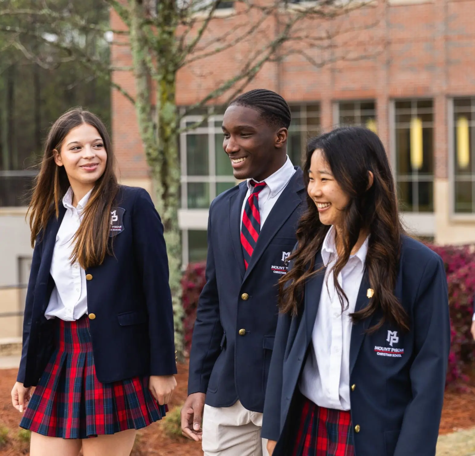 Three students walking outside, smiling
