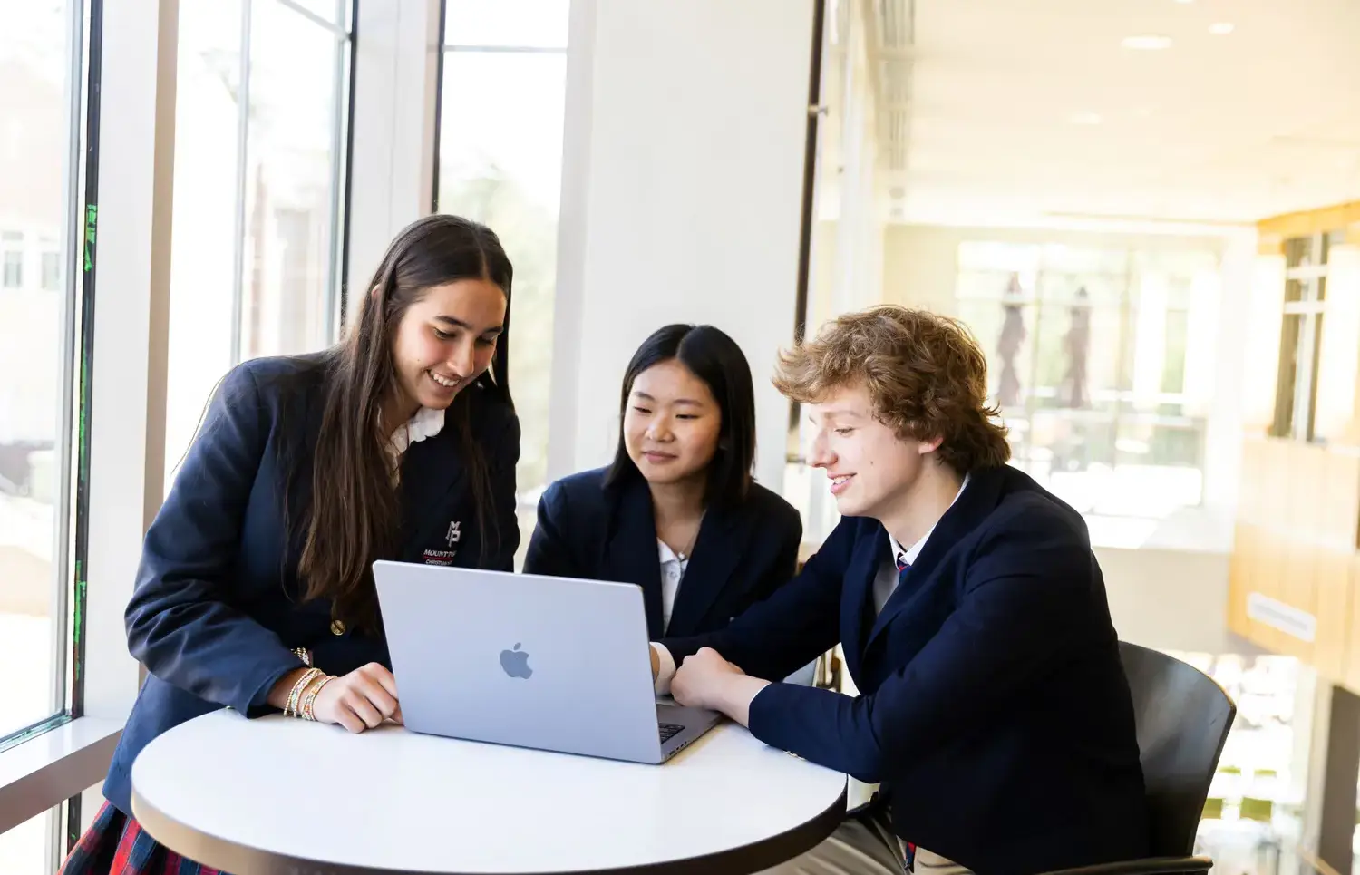 Three students sitting around a laptop