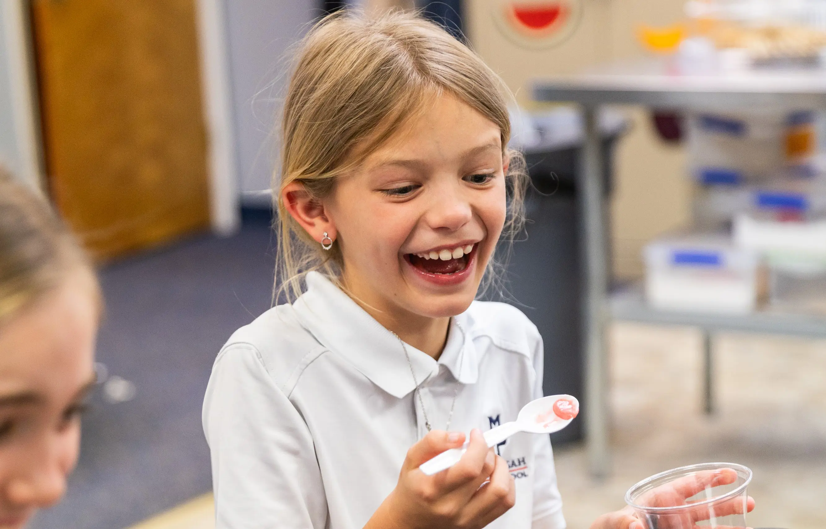 Young girl laughing with a spoonful of food in her hand