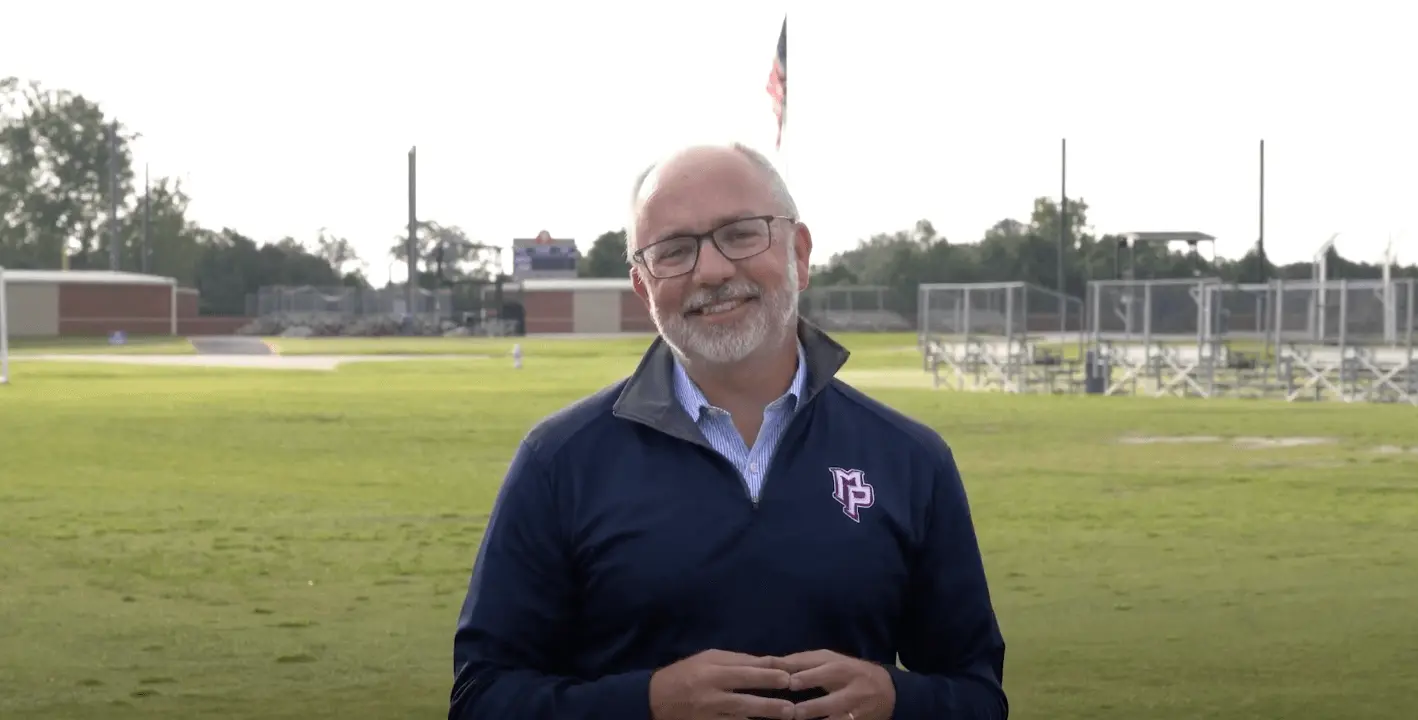 Man talking in front of athletics field