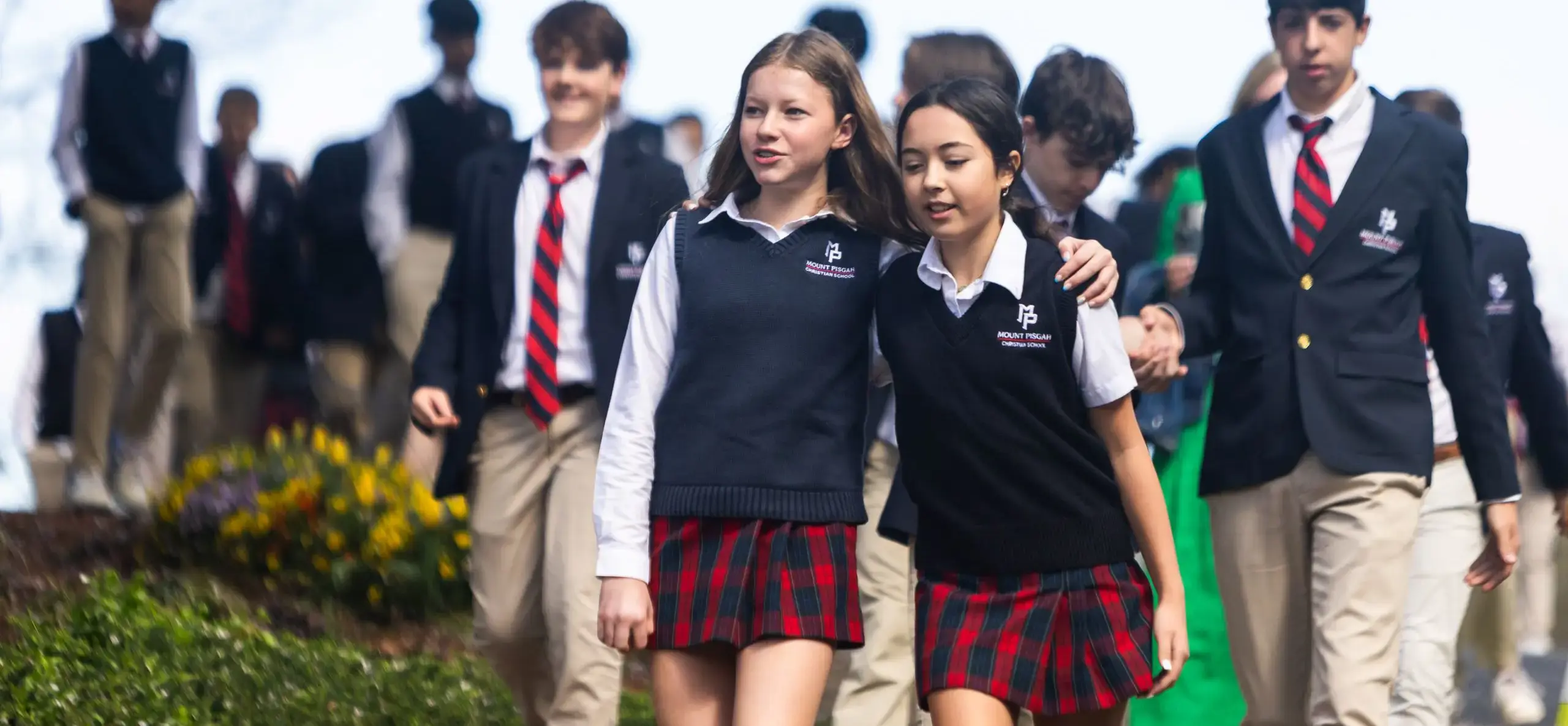 Two students walking outside arm in arm