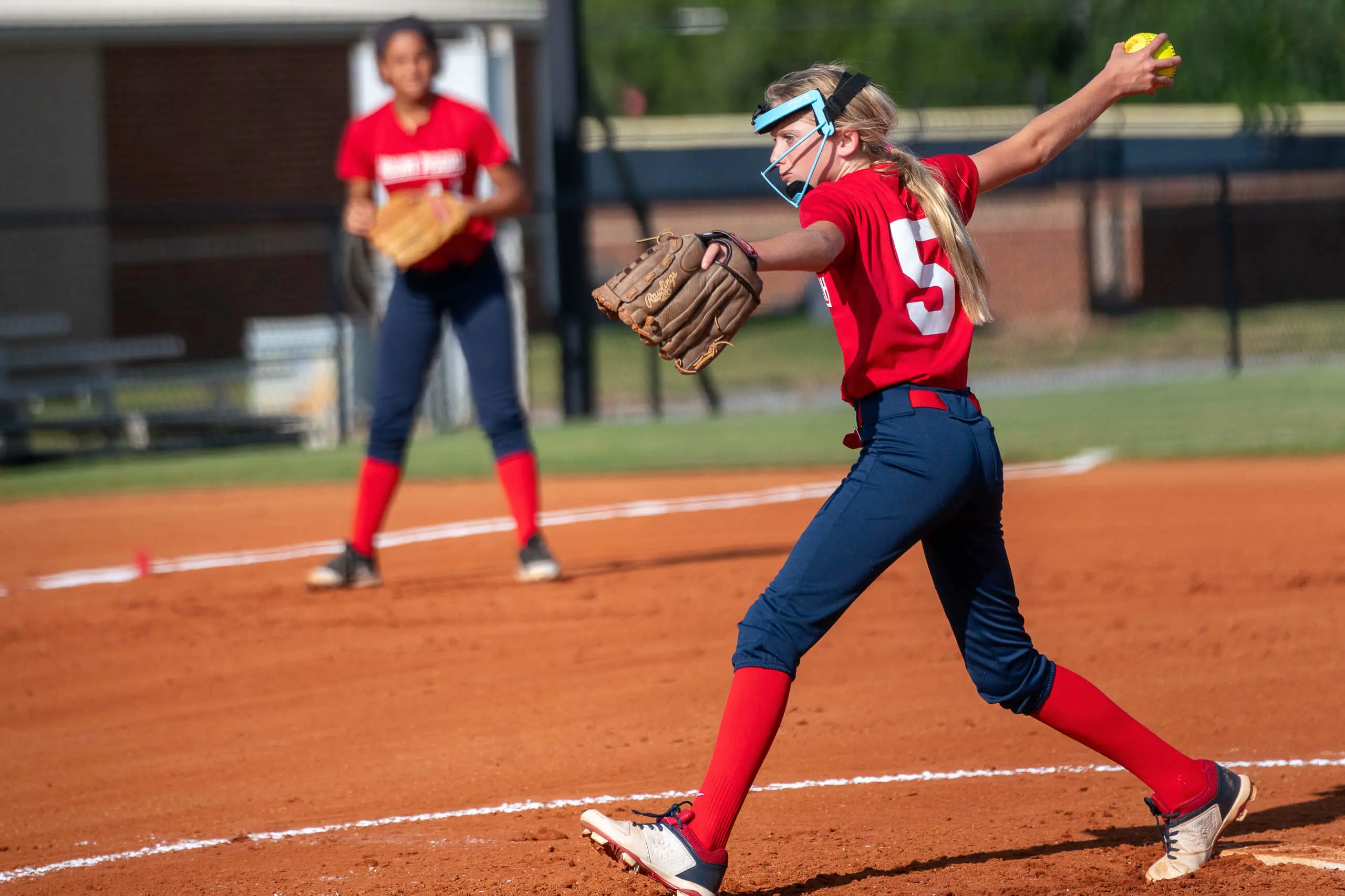 softball player throws pitch