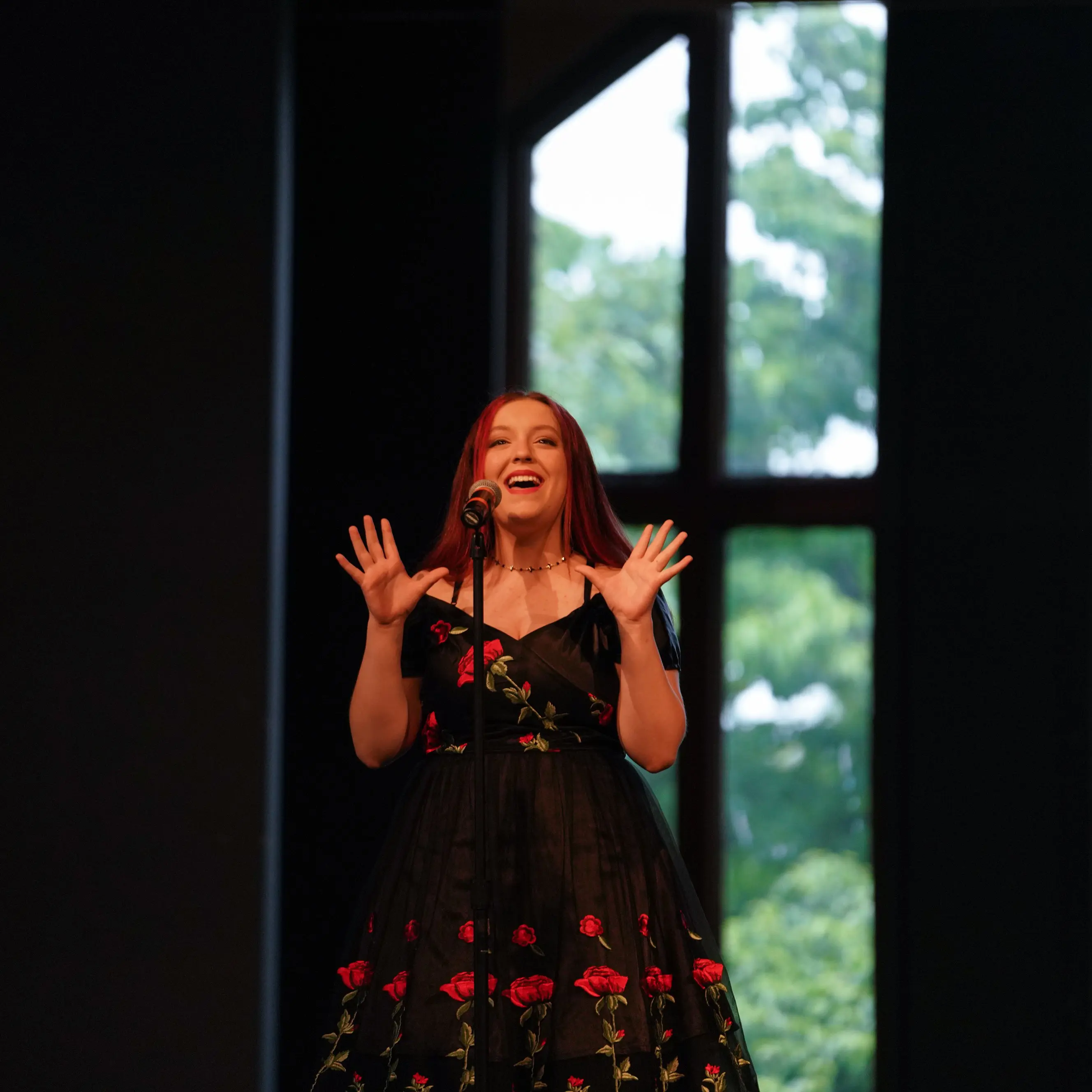 A high-school-aged girl sings on a stage