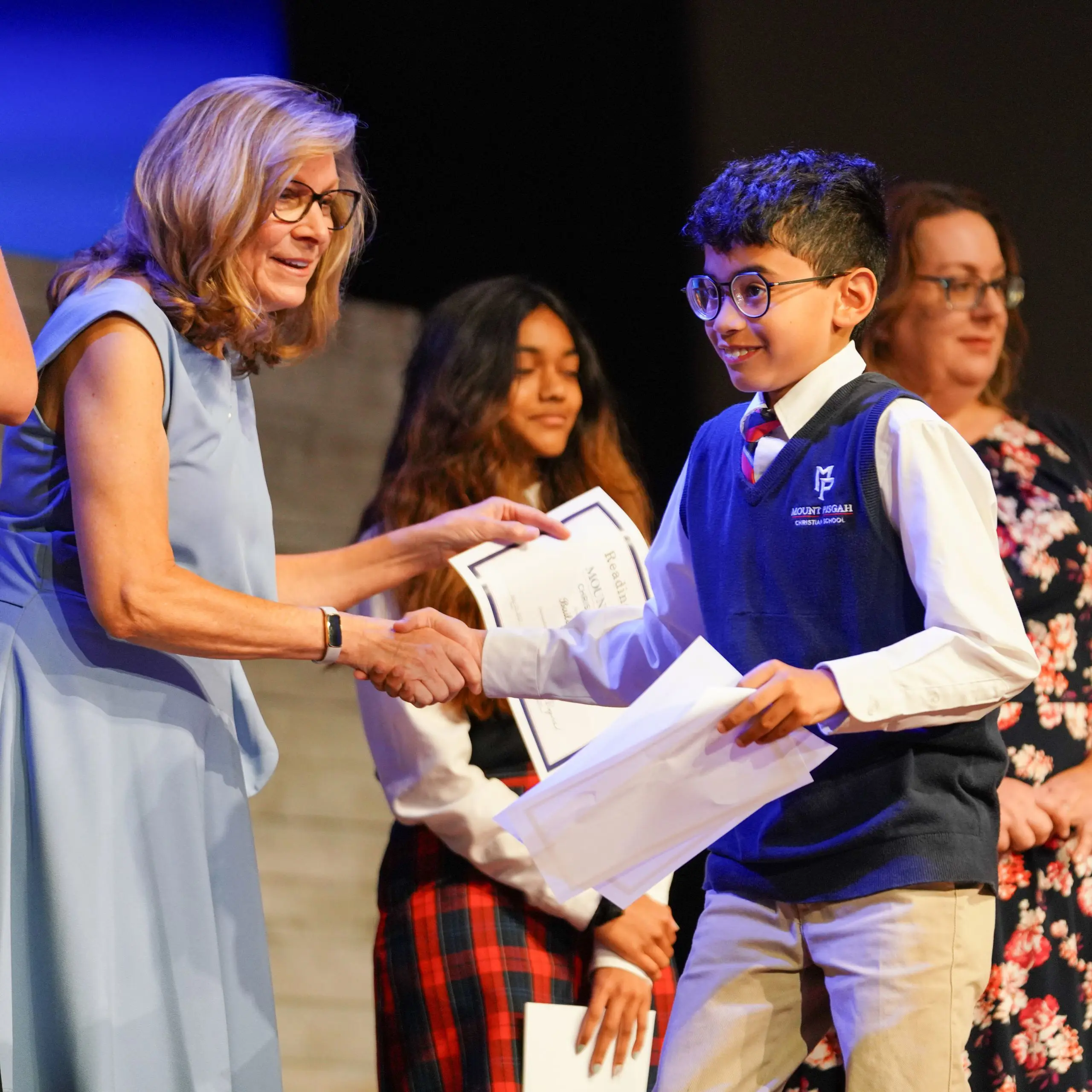 Teacher presenting a certificate to student, shaking their hand