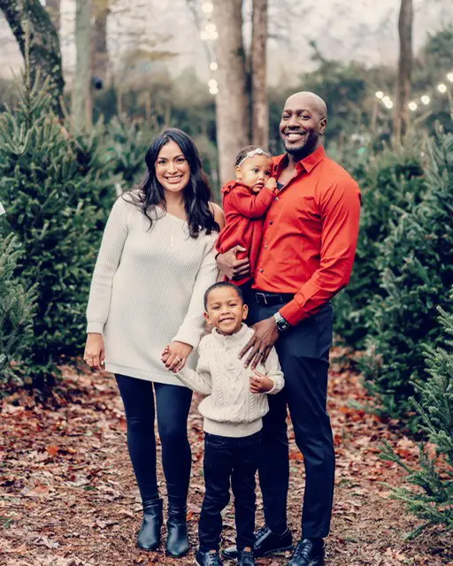 Family of four standing against a wooded background