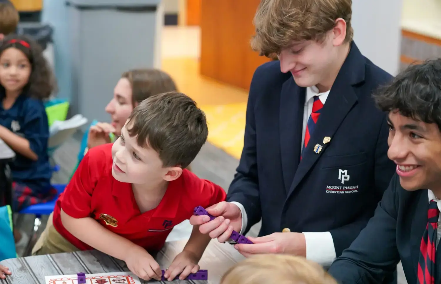 Upper school student helping younger students in classroom