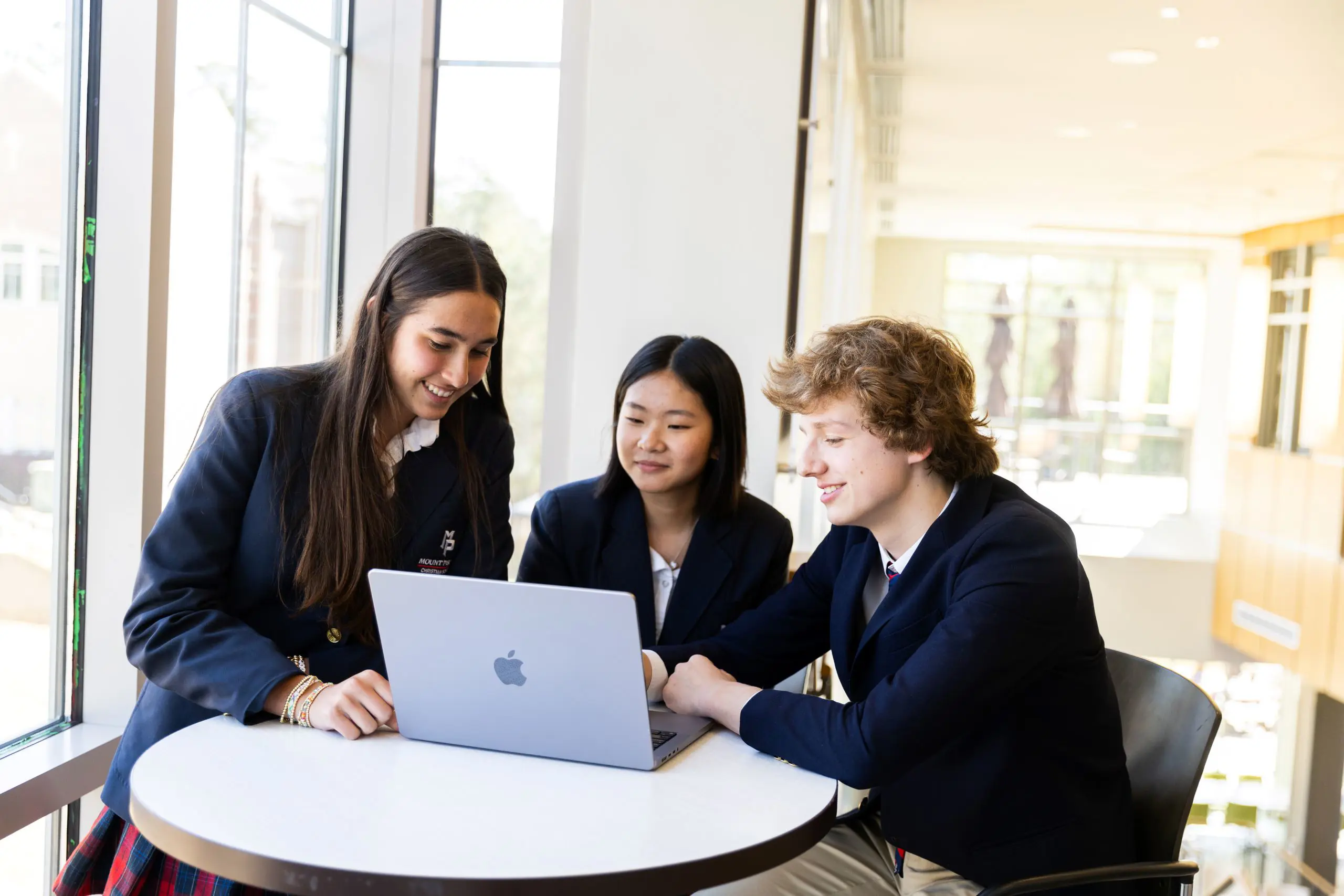 Three students sitting around a laptop