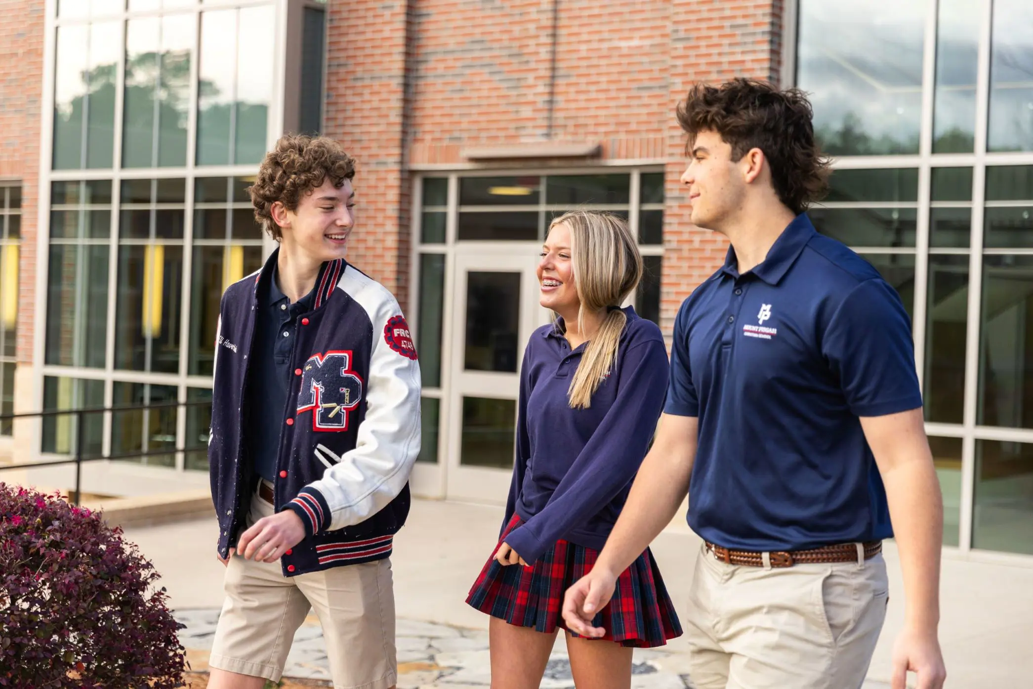 Three students walking outside, smiling