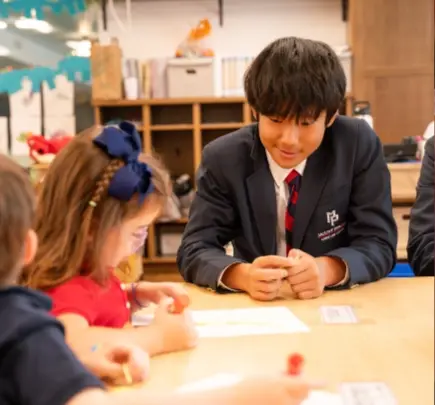 Older and younger student smile together at a table.